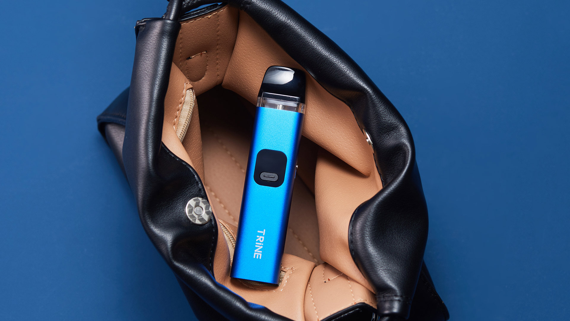 Innokin Trine nachfüllbare vape in einem schlanken blauen Design in einer offenen schwarzen Ledertasche mit beige Innenraum, auf einem soliden blauen Hintergrund für einen stilvollen und modernen Look angezeigt.