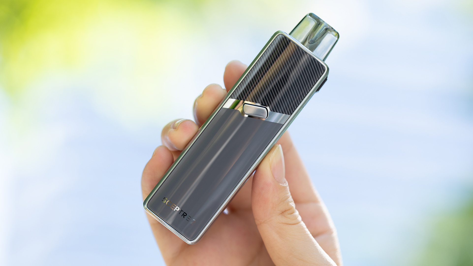 Eine Hand hält das elegante Innokin Sceptre 2 Verdampfergerät, das für Nikotinsalze entwickelt wurde, vor einem sanft verschwommenen grünen und blauen Hintergrund.