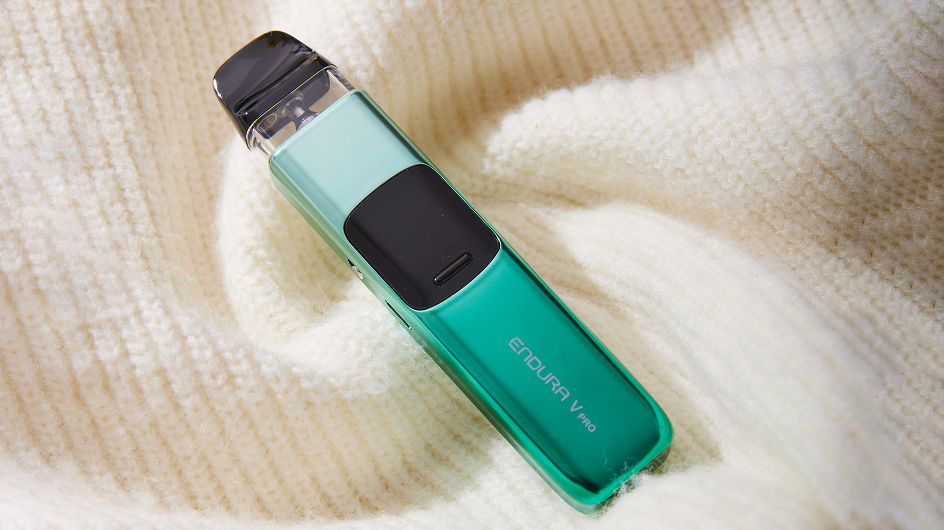 Innokin Endura V Pod Vape in leuchtendem Grün, vor einem Hintergrund aus weichem Strickstoff.