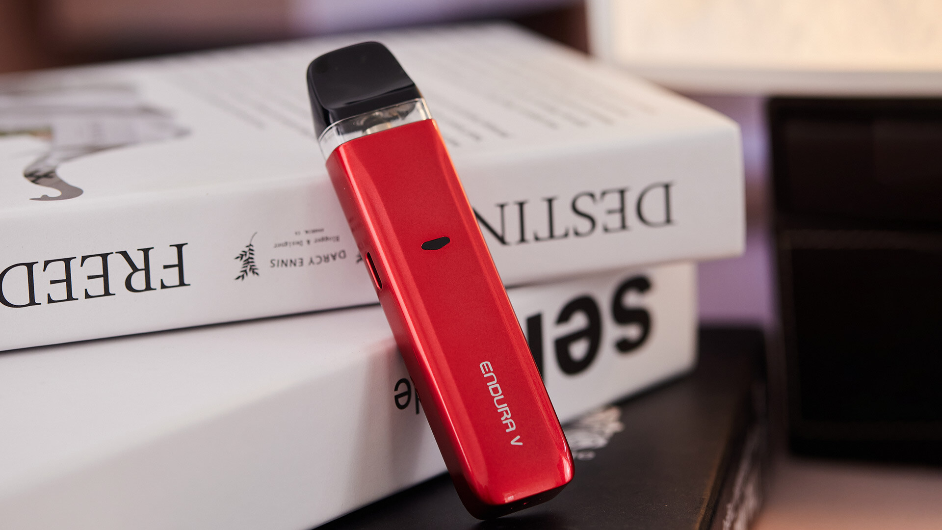 Ein rotes Endura V E-Zigaretten-Set, das an Bücher gelehnt ist.