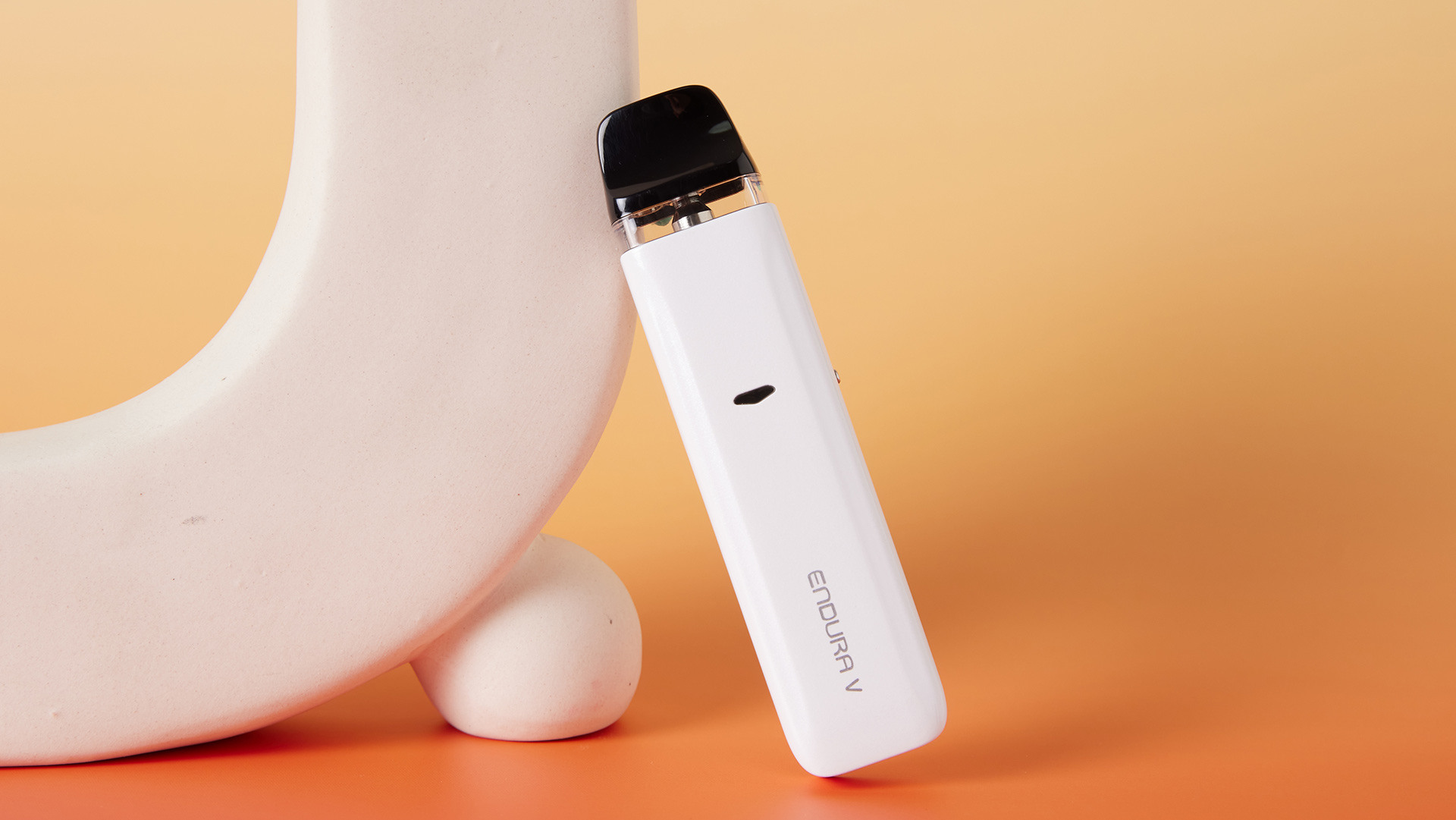 Weißes elektronisches Gerät Innokin Endura V , das an ein helles, rundes Objekt gelehnt ist.